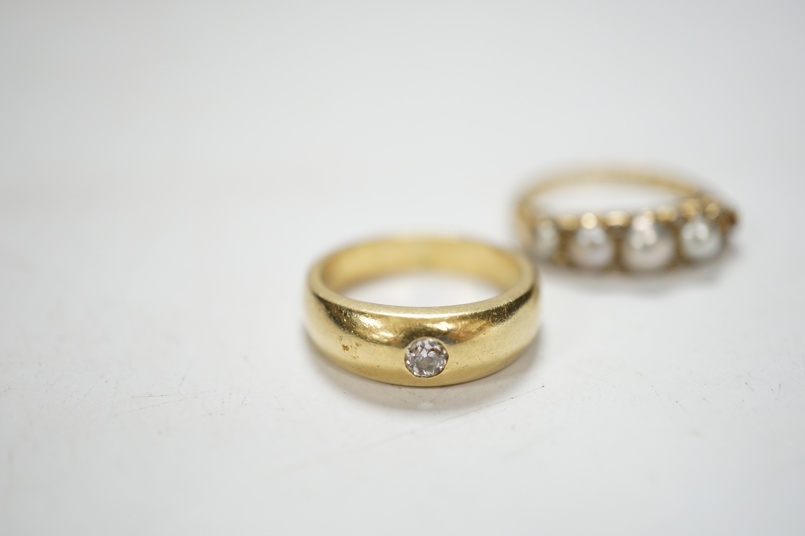 An early 20th century yellow metal and graduated split pearl set half hoop ring, with diamond chip spacers (pearl missing), size K/L, gross weight 4.5 grams, together with a yellow metal and gypsy set solitaire diamond r